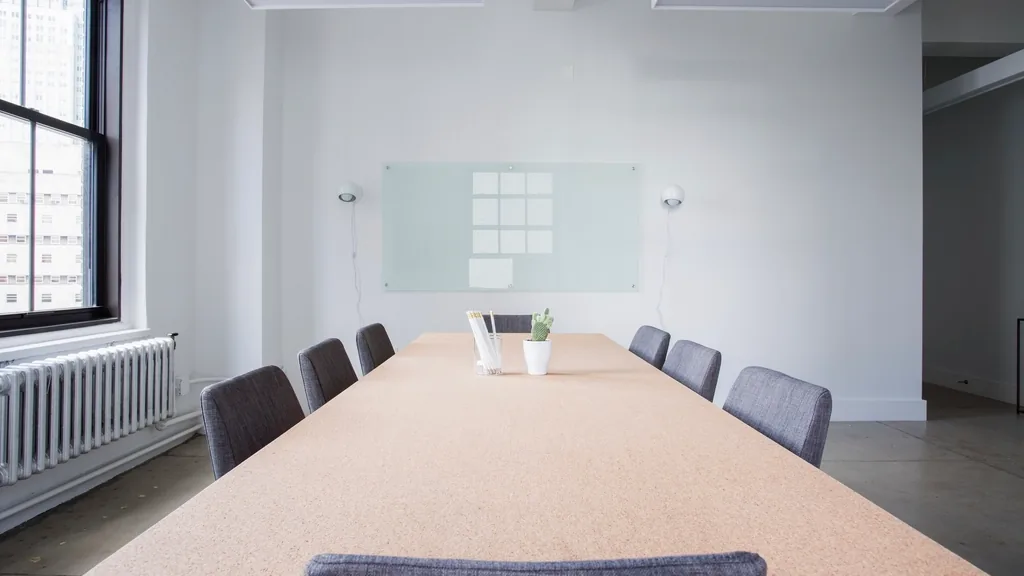 An empty boardroom with a long table and a blank whiteboard